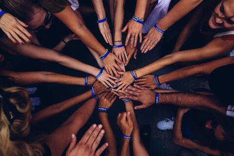 Photo of students putting hands together in a circle